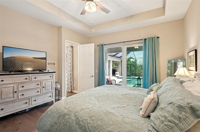 bedroom featuring a raised ceiling, access to exterior, dark hardwood / wood-style floors, and ceiling fan