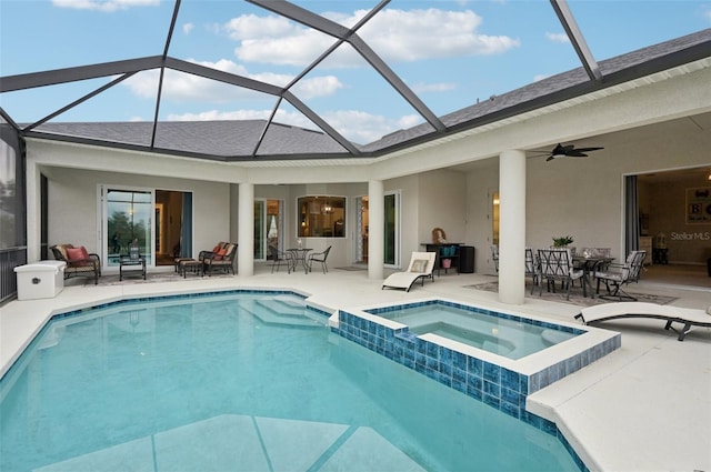 view of swimming pool featuring ceiling fan, a patio area, glass enclosure, and an in ground hot tub