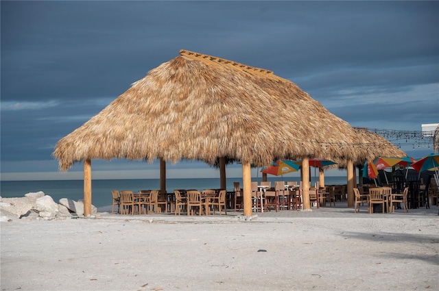 surrounding community with a gazebo, a water view, and a beach view