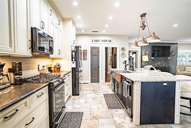 kitchen featuring a center island with sink, a breakfast bar area, appliances with stainless steel finishes, hanging light fixtures, and dark stone counters