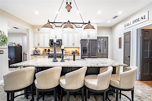 kitchen with pendant lighting, a kitchen bar, stainless steel appliances, backsplash, and light stone counters