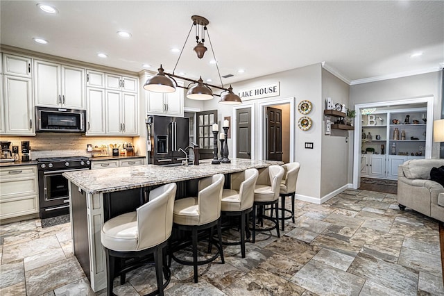 kitchen with tasteful backsplash, a kitchen island with sink, a kitchen breakfast bar, pendant lighting, and black appliances