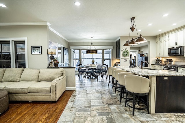 kitchen featuring a large island, light stone countertops, pendant lighting, a breakfast bar, and black appliances