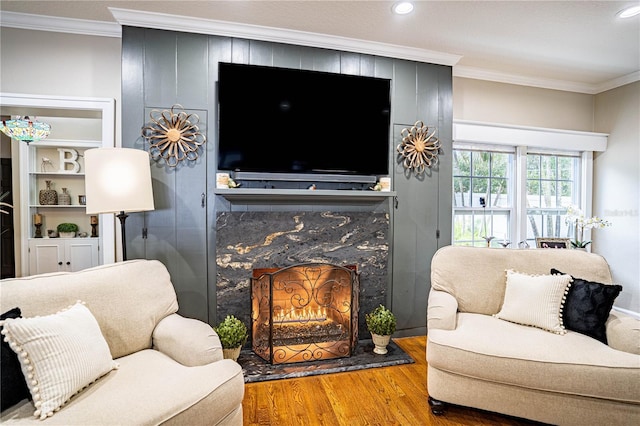 living room featuring wood-type flooring, crown molding, and a fireplace