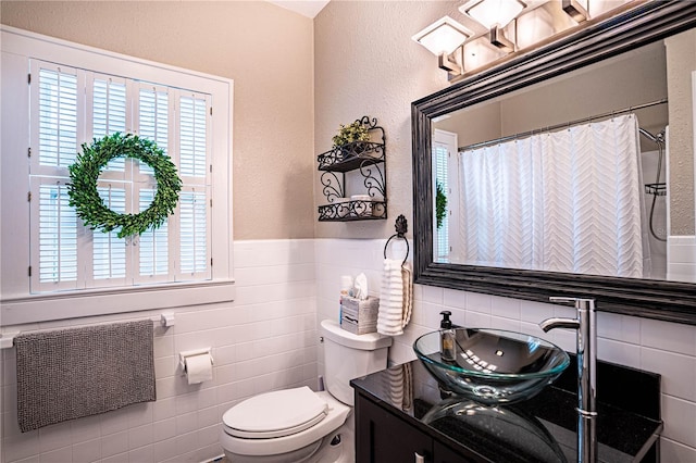 bathroom with tile walls, toilet, vanity, and a shower with shower curtain