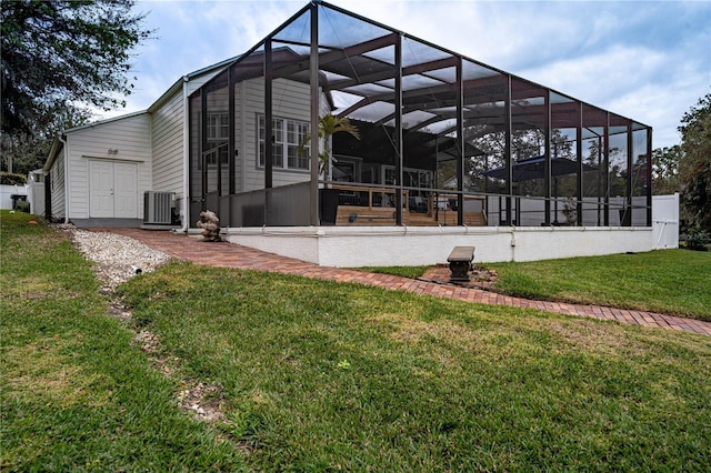 rear view of property featuring a lawn, cooling unit, and glass enclosure