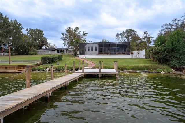 view of dock featuring a lanai, a water view, and a lawn