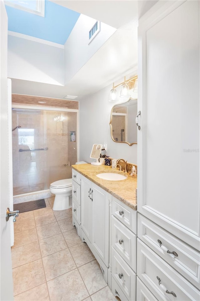 bathroom featuring a shower with door, toilet, vanity, and tile patterned flooring