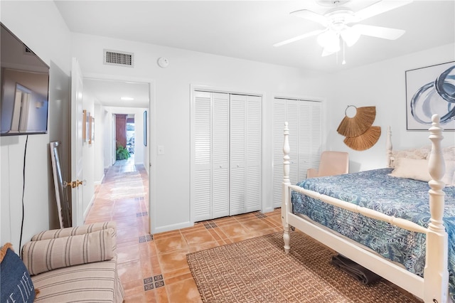 tiled bedroom featuring ceiling fan and two closets