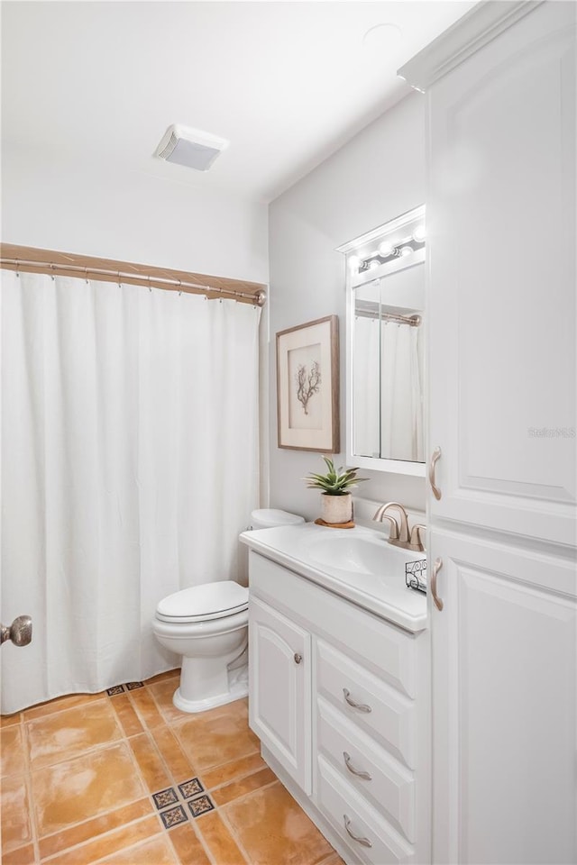 bathroom with toilet, vanity, and tile patterned flooring