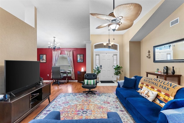 living room featuring vaulted ceiling, ceiling fan with notable chandelier, and hardwood / wood-style floors