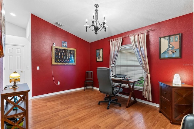 home office featuring lofted ceiling, a chandelier, and hardwood / wood-style flooring