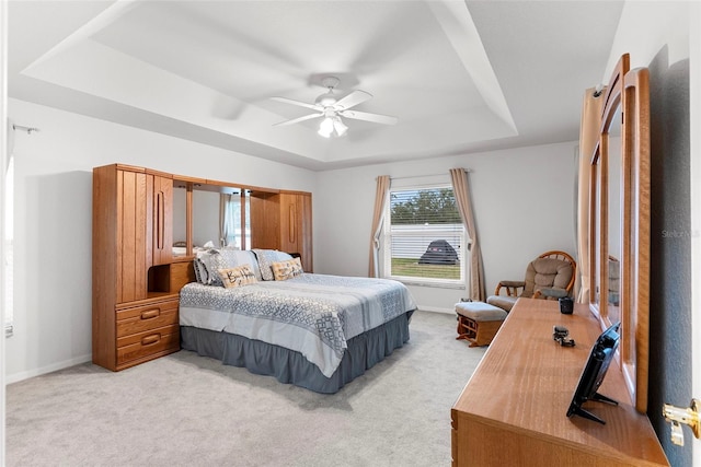 bedroom featuring ceiling fan, light colored carpet, and a raised ceiling