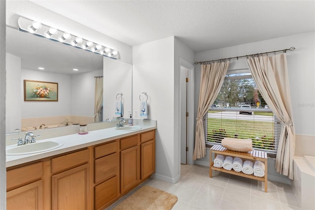 bathroom with tiled bath, a textured ceiling, tile patterned floors, and vanity