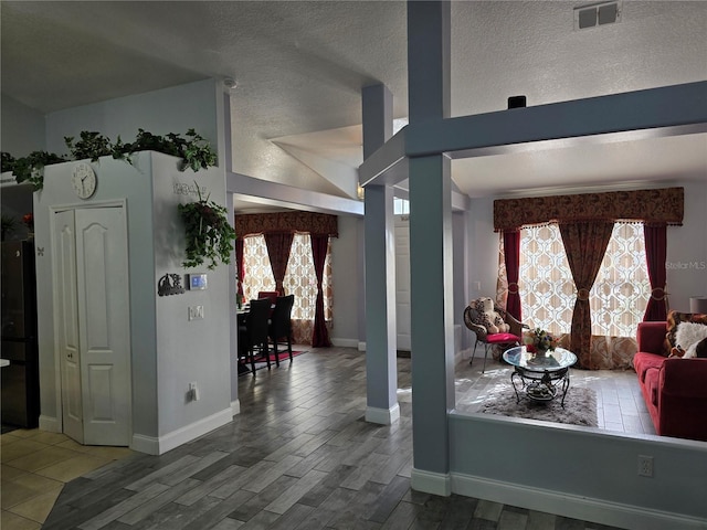 interior space with a wealth of natural light, hardwood / wood-style floors, and decorative columns