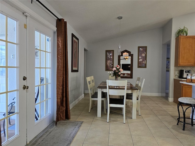 dining room featuring vaulted ceiling, light tile patterned floors, and french doors