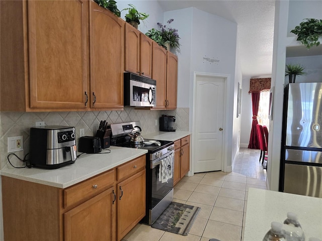 kitchen with light tile patterned floors, appliances with stainless steel finishes, and tasteful backsplash