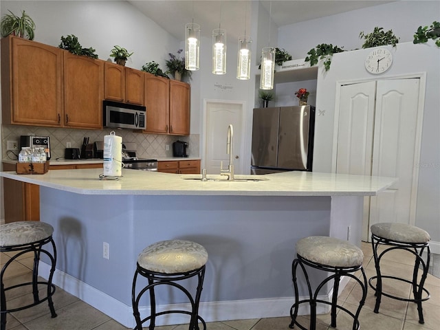 kitchen with light tile patterned floors, appliances with stainless steel finishes, tasteful backsplash, pendant lighting, and sink