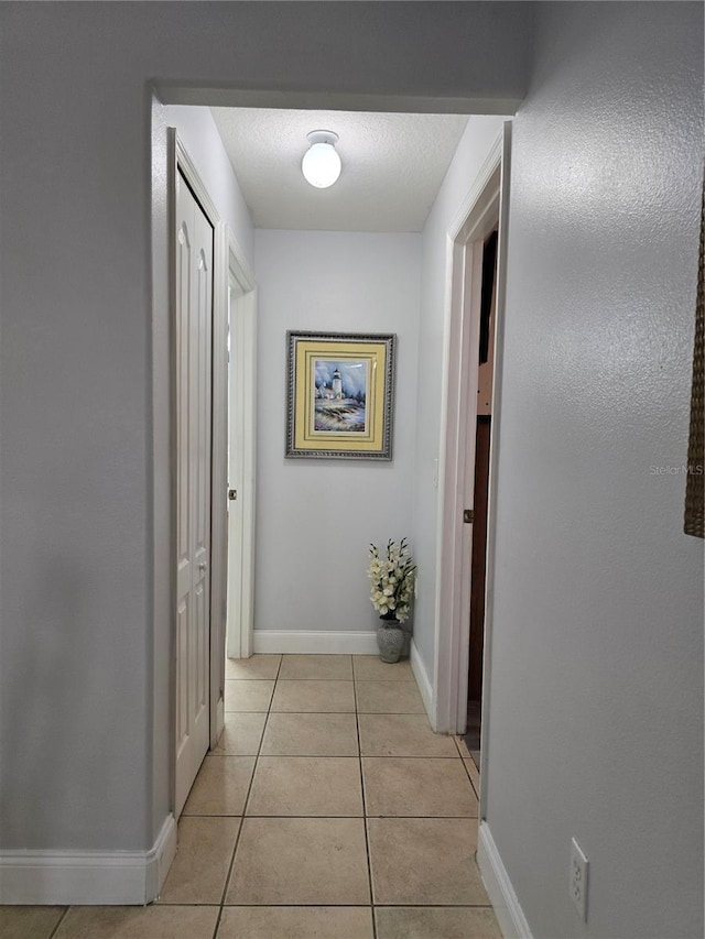 hall featuring light tile patterned floors and a textured ceiling