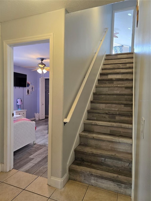 staircase with ceiling fan and tile patterned flooring