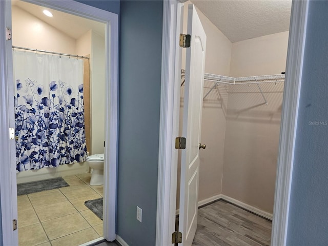 bathroom featuring a textured ceiling, toilet, and tile patterned flooring