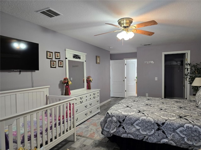 bedroom featuring a textured ceiling, hardwood / wood-style floors, a walk in closet, a closet, and ceiling fan