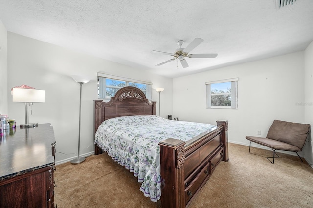 bedroom with ceiling fan, a textured ceiling, and light carpet