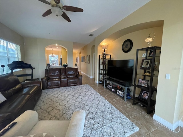 tiled living room featuring ceiling fan with notable chandelier