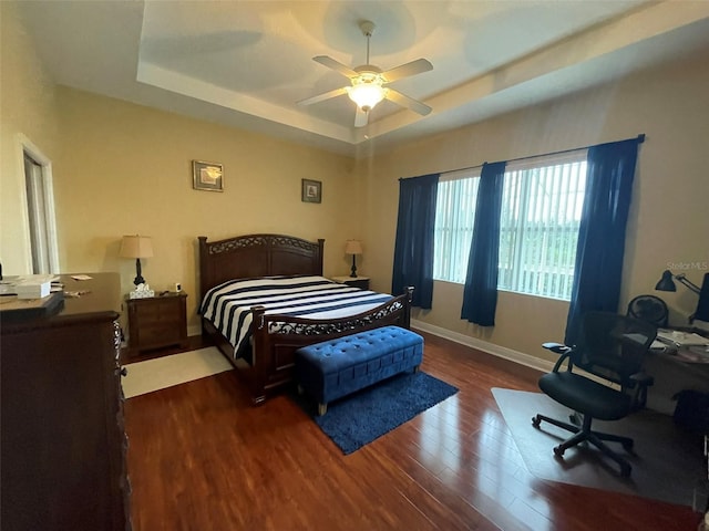 bedroom featuring ceiling fan, dark hardwood / wood-style flooring, and a raised ceiling