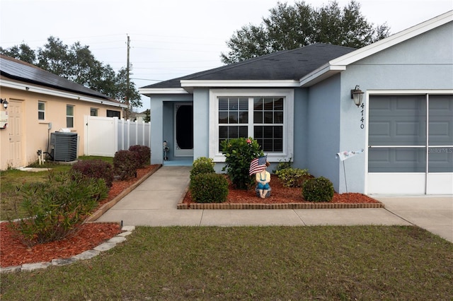 view of exterior entry with central AC unit, a yard, and a garage