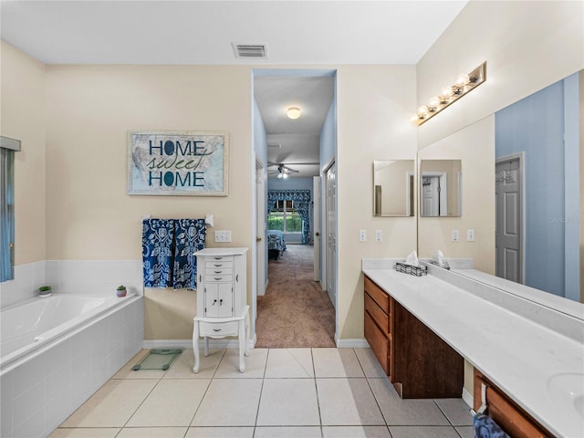 bathroom featuring vanity, a relaxing tiled tub, tile patterned floors, and ceiling fan