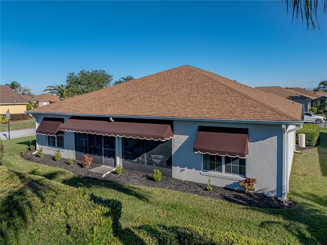 rear view of property with a lawn and a sunroom