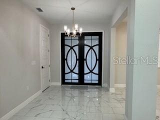 entryway with french doors and a chandelier