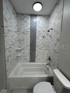 bathroom featuring tiled shower / bath combo and toilet