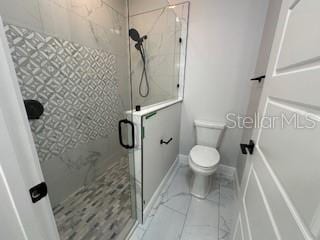 bathroom featuring toilet and a shower with door