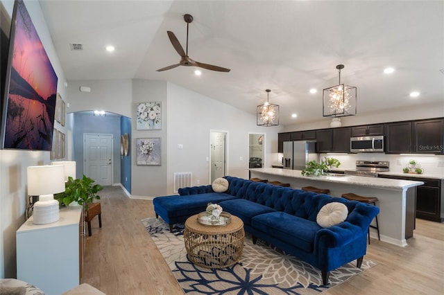 living room with ceiling fan, vaulted ceiling, and light hardwood / wood-style flooring