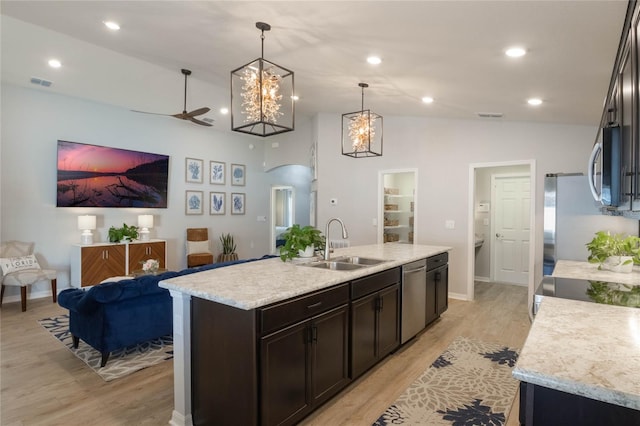 kitchen with sink, decorative light fixtures, vaulted ceiling, a center island with sink, and stainless steel appliances