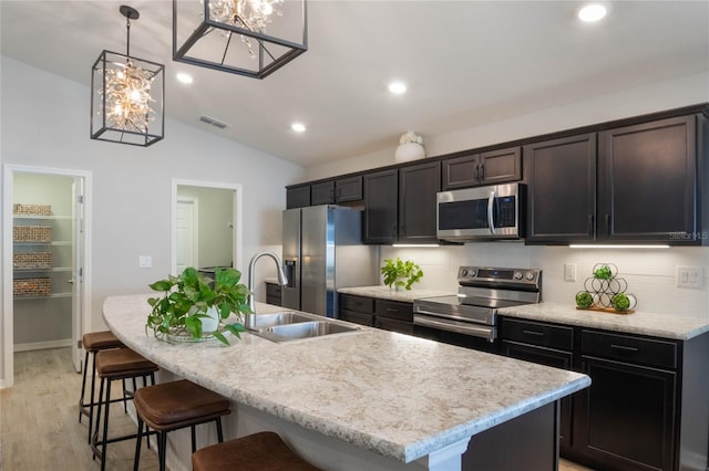 kitchen with light wood-type flooring, a center island with sink, and appliances with stainless steel finishes