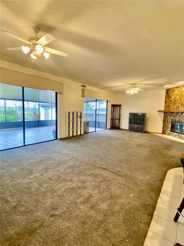 unfurnished living room with carpet floors, a wealth of natural light, ceiling fan, and a fireplace