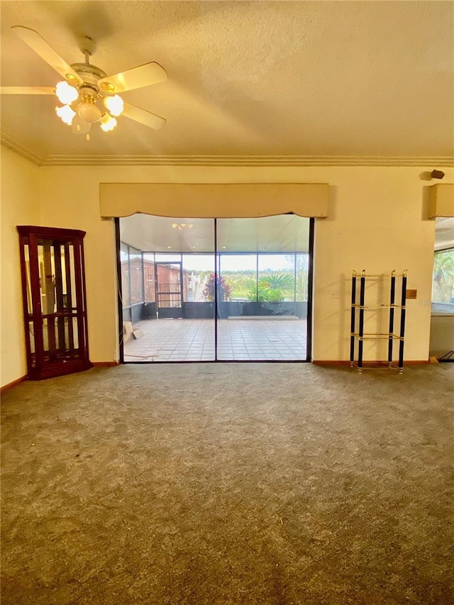 unfurnished living room with ceiling fan, carpet, ornamental molding, and a textured ceiling