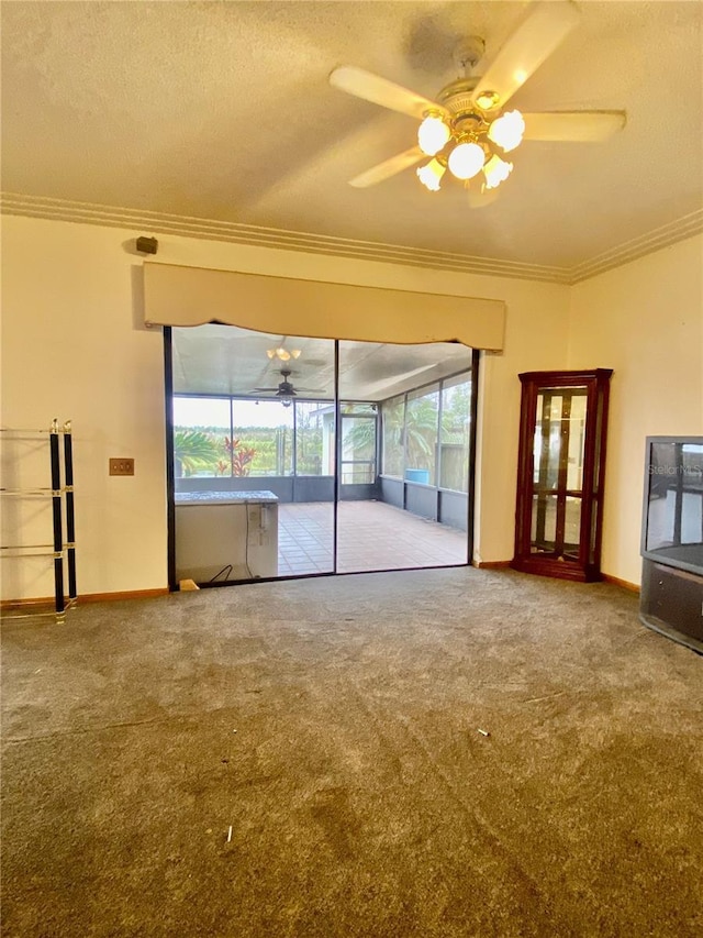 unfurnished living room with ceiling fan, carpet flooring, ornamental molding, and a textured ceiling