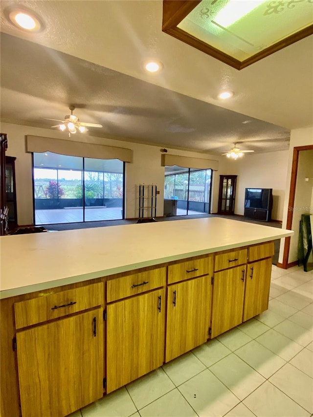 kitchen with ceiling fan, a textured ceiling, kitchen peninsula, and light tile patterned flooring