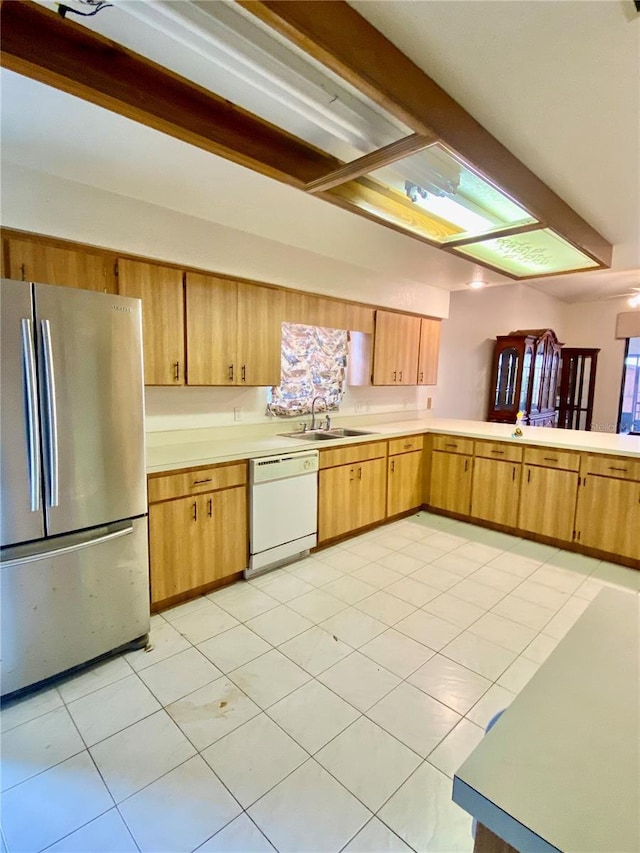 kitchen with white dishwasher, sink, light tile patterned flooring, and stainless steel refrigerator