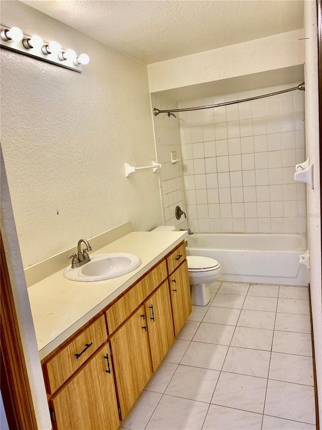 full bathroom with toilet, a textured ceiling, tile patterned flooring, vanity, and tiled shower / bath