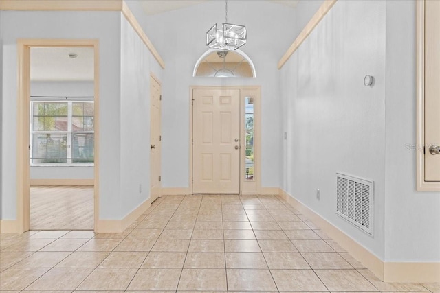 tiled entryway with a towering ceiling and a chandelier