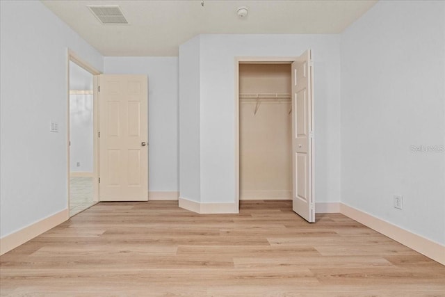 unfurnished bedroom with light wood-type flooring and a closet