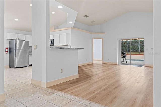 unfurnished living room featuring light tile patterned floors and high vaulted ceiling