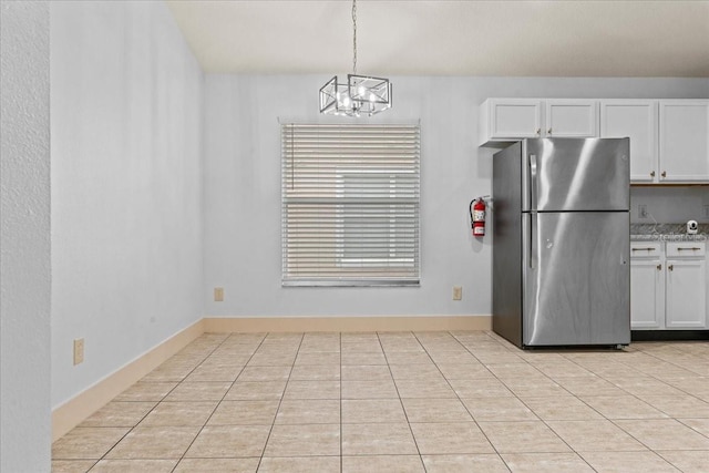 kitchen with pendant lighting, an inviting chandelier, white cabinetry, light tile patterned floors, and stainless steel fridge