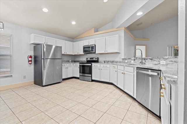 kitchen featuring lofted ceiling, sink, appliances with stainless steel finishes, white cabinets, and light stone counters