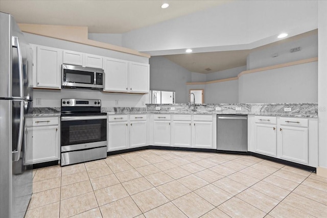 kitchen featuring appliances with stainless steel finishes, lofted ceiling, and white cabinetry